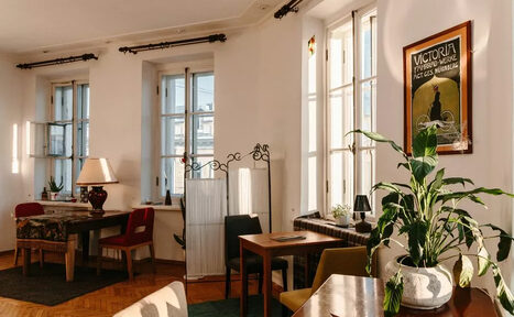 Арендовать Светлый лофт с панорамным видом. Большие окна. Столы с лампой и цветком, стулья