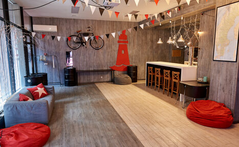 Арендовать Стильный лофт в скандинавском стиле. Вход с улицы. Красные пуфики, серое кресло.