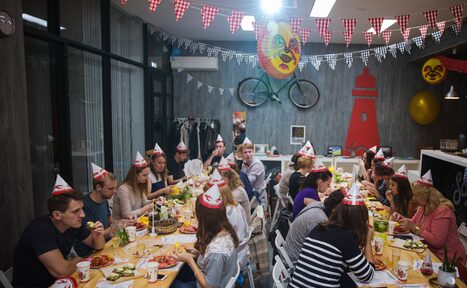 Арендовать Стильный лофт в скандинавском стиле. Вход с улицы. Праздничный стол на день рожденья, гости в бумажных колпаках.