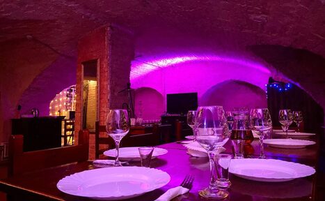 Арендовать Loft Зазеркалье. Пурпурное освещение. Крупный план на накрытый посудой стол. Бокалы, вилки. ножи. 