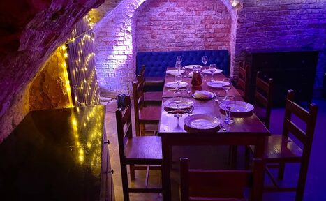 Арендовать Loft Зазеркалье. Накрытый посудой стол. Рядом стулья и тумбочка