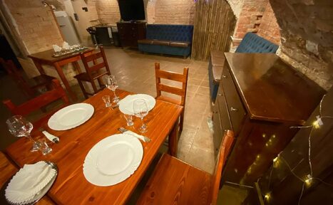 Арендовать Loft Зазеркалье. Вид сверху. Стол, на котором разложена посуда. Рядом стоят стулья и тумбочка