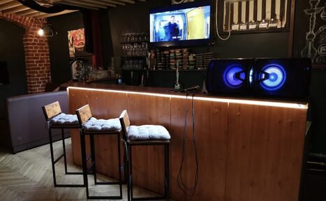 Арендовать Караоке-бар в центре города. Диваны с небольшими квадратными столами. Телевизор 