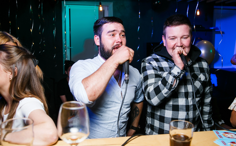 Арендовать Караоке-бар в центре города. Мужчина и девушка поют в караоке