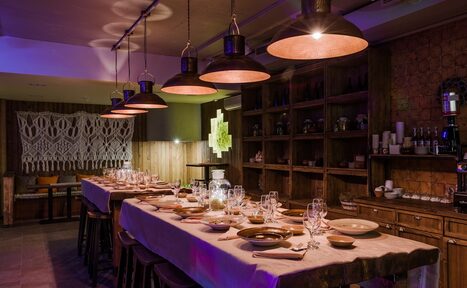 Арендовать Нора. Оборудованный зал. Затемнённое освещение. Столы с сервировкой. Подвесные лампы