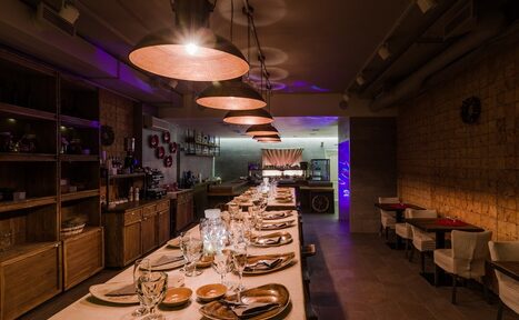 Арендовать Нора. Оборудованный зал. Затемнённое освещение. Столы с сервировкой. Подвесные лампы. Небольшие столики "на двоих"