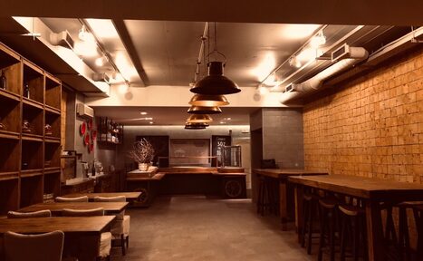 Арендовать Нора. Оборудованный зал. Свободное пространство. Высокие столы со стульями. Обычные столы со стульями