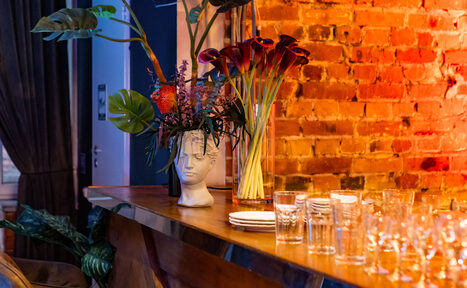 Арендовать Лофт со сценой. Широкая барная стойка с барными стульями. Стол с едой и посудой