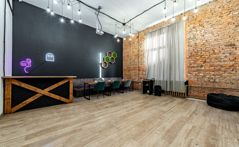 Арендовать Rubin Loft (Рубин Лофт). Лофт средний. Просторное помещение с кирпичными стенами и деревянным полом. Стена окрашена в чёрный с неоновым освещением. Есть барная стойка, столы и стулья, диван. Подвесное освещение. Большое окно с занавесками.