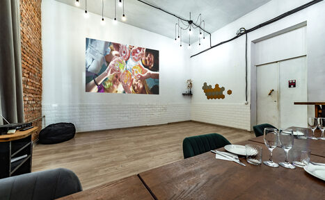 Арендовать Rubin Loft (Рубин Лофт). Лофт средний. Пространство с белыми стенами, одна из которых облицована белым кафелем и кирпичом. На стене проектируется изображение. Натяжные лампы на потолке. Стол с приборами и бокалами. Черный пуф у стены. Светлое деревянное покрытие пола.