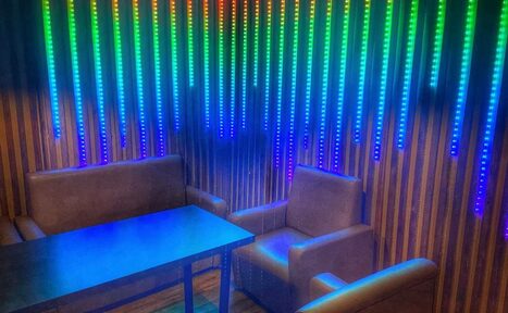 Арендовать Forest(Лес). Пространство с деревянными стенами, декорированными вертикальными LED-панелями с меняющейся цветной подсветкой. Два кресла и диван обиты мягкой тканью, с деревянным столом в центре. Пол выполнен в деревянной отделке.