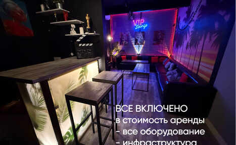 Арендовать Лофт ИЗНАНКА. Зал ГОЛЛИВУД. Караоке-зал с черными стенами и неоновым освещением. Барная стойка с высокими стульями, мягкие диваны у стен. На потолке прожекторы. Стены декорированы постерами и растительными узорами. Текст на фото: "ВСЕ ВКЛЮЧЕНО в стоимость аренды".