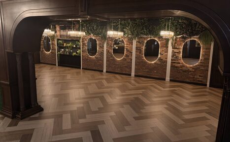 Арендовать Soul Event (Соул Ивент). Малый зал. Просторное помещение с паркетным полом в ёлочку, кирпичными стенами с окнами-арками, декорированными зеленью. Подвесные светильники с кристаллами обеспечивают освещение. Потолок темный с декоративными элементами. Состояние аккуратное и чистое.