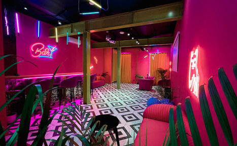 Арендовать Плэйс Лофт. Prisma Loft(Призма Лофт). Коктейль-бар с ярко-розовыми стенами, черно-белая плиточная мозаика на полу. Барная стойка с высокими стульями, неоновые вывески, разнообразные светильники. По периметру установлены диваны, интерьер дополняют растения.