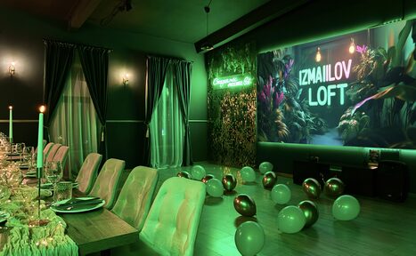 Арендовать Лофт Гринвуд. Loft-пространство с длинным деревянным столом, стульями с мягкой обивкой, шпалерами на стене и зелеными шторами. На стене неоновая надпись, вокруг расставлены воздушные шары. Освещение теплое, потолочные светильники.