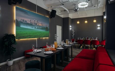 Арендовать Rubin Loft (Рубин Лофт). Лофт Вегас. Просторное помещение с серыми стенами, столами из темного дерева, красными мягкими диванами и стульями. Подвесные светильники и потолочные светильники. Крупная картина с подсветкой на стене. Посуду и бокалы расставлены на столах.
