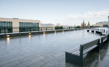 Арендовать Площадка в Москве. Открытая терраса с каменным покрытием и серыми деревянными скамейками. Металлические ограждения вдоль края. Освещение встроено в пол. На горизонте видны архитектурные купола. День, ясное небо.