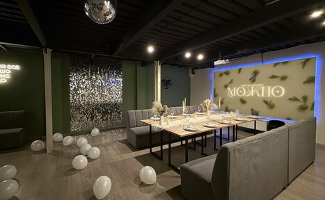 Арендовать Maybe Loft (Мэйби Лофт). Зал Olive (Олив). Современный дизайнерский лофт . Частное помещение с серыми диванами и длинным деревянным столом, украшенным посудой. На полу белые воздушные шары. Неоновая надпись "МОЖНО" на стене с подсветкой. Потолок и пол темные. Зеркальная стена и шар-дискобол под потолком.