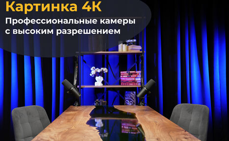Арендовать Лофт Восторг. Современное офисное пространство с деревянным столом, двумя серыми стульями и полкой, на которой стоят книги и декор. Сзади темно-синие занавески. Использовано направленное освещение. Текст на изображении: "Картинка 4К, Профессиональные камеры с высоким разрешением".