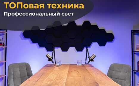 Арендовать Лофт Позитив. Таблица из светлого дерева в центре комнаты, по сторонам серые кресла. На столе два микрофона, два стеклянных стакана. На заднем плане чёрные шестиугольные панели на фиолетовой стене. Справа книжная полка. Освещение направленное. Текст: "ТОПовая техника, Профессиональный свет".