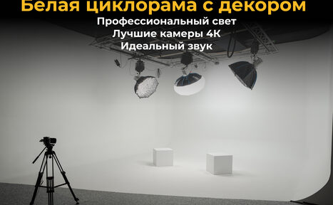 Арендовать Лофт Циклорама. Студийное пространство с белой циклорамой. Две белые кубические тумбы на полу. Осветительное оборудование на подвесной конструкции. Чёрный штатив для камеры. Текст: "Белая циклорама с декором. Профессиональный свет. Лучшие камеры 4К. Идеальный звук".