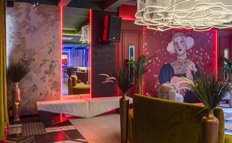 Арендовать Стильное пространство Астрид. Креативное пространство с яркими акцентами: постеры, неоновая подсветка, кресла, декоративные растения в вазонах. Стены ярких цветов с текстурами и рисунками. Современная мебель, плитка с узором на полу и оригинальные светильники на потолке.