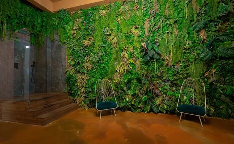Арендовать Polygon(Полигон). Зал Марокко. Стена с живыми растениями, две стальные кресла с зелеными подушками, пол коричневого цвета, душевая кабина с прозрачными стеклами и мраморными стенами, деревянные ступени.