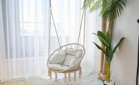 Арендовать Лофт Мальдивы с открытым душем, балконом и видом на Сити. Круглое подвесное кресло с подушками на веревочных цепях, белые шторы от потолка до пола, декоративные белые камни на полу, деревянное половое покрытие, зеленое растение в горшке, белая стена.