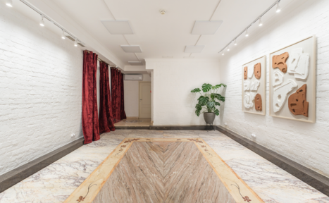 Арендовать Светлый Лофт. Прямоугольное помещение с белыми кирпичными стенами, красными шторами, мраморным полом, точечным освещением. На стене подвешены абстрактные картины. В углу стоит зеленое растение в сером горшке.