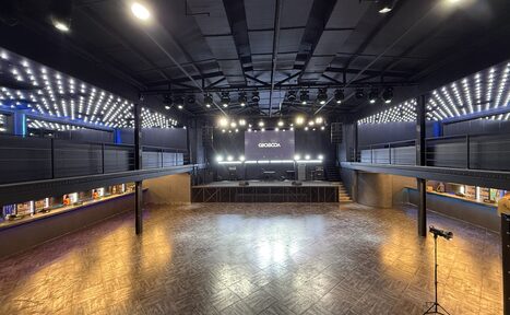 Арендовать СВОБОДА. Зал на 1200 человек. Большое открытое пространство с паркетным полом. Высокий потолок с черными балками и подвесными светильниками. Центральная сцена с экраном и музыкальным оборудованием. По периметру балконы с поручнями. Интенсивное потолочное освещение.