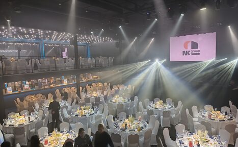 Арендовать СВОБОДА. Зал на 1200 человек. Большой зал с круглым столами, покрытыми скатертями; на каждом столе свечи и сервировка. Белые стулья, световые лучи по залу. Двухуровневое пространство, на верхнем уровне также столы и стулья. На стене висит экран с логотипом.