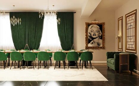 Арендовать Голливуд. Элегантный лофт в зелено-бежевых оттенках. Столовая с длинным деревянным столом и десятью зелёными стульями, зелёные шторы на окнах, два подвесных светильника, черно-белое фото в позолоченной раме, зелёный диван в углу, светлые стены, пол из светлого мрамора и тёмного гранита.