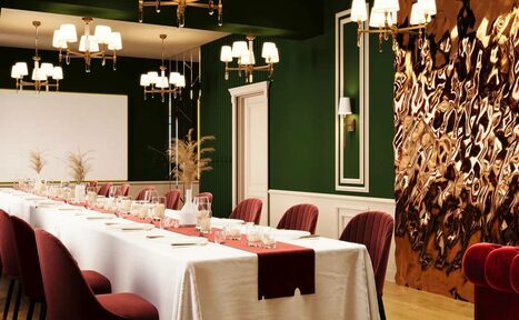 Арендовать Вегас. Атмосферный лофт с акцентным дизайном. Просторная комната с длинным столом, накрытым белой скатертью и бордовыми сервировочными дорожками. Вокруг бордовые стулья. Тёмно-зелёные стены, золотые и белые светильники, декоративная панель с текстурой. Светлое деревянное покрытие пола.