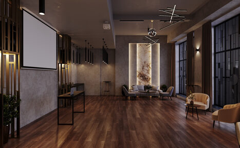 Арендовать Лофт Мираж. Просторное помещение с деревянным полом, серыми стенами и современной мебелью: диваны, кресла и столы. Большие окна, проектор и экран, стильные светильники на потолке, декоративная подсветка на стене.