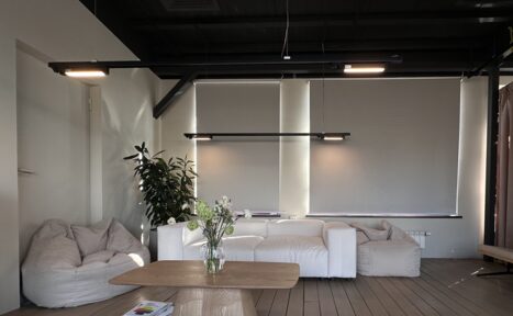 Арендовать Пространство с террасой до 50 человек. Просторная комната с мягким освещением, белым диваном и креслами-мешками. Светлые стены и потолок. Деревянный журнальный стол украшен вазой с цветами. Нейтральные цвета. Растение в горшке возле дивана. Шторы закрывают окна.