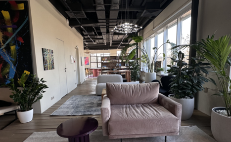 Арендовать Пространство с террасой до 50 человек. Лофт-пространство с окнами вдоль одной стены. Мягкий диван, журнальный столик и ковры на деревянном полу. Крупные горшечные растения. Декоративные картины на стенах. Подвесные светильники, белый и серый цвета, современный интерьер.