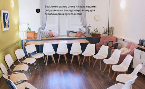 Арендовать H4U. Светлый зал П-602. Просторная светлая комната с круговой расстановкой белых стульев. На деревянном полу расположен стол с подушками у окон. На стене картина и часы. Светлые стены, зелёное кресло, розовый диван, комнатные растения. Вывеска с текстом на русском.
