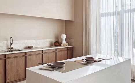 Арендовать Киото. Светлый зал с кухней. Кухонное пространство с белым островом, укомплектованным кухонной посудой. Справа раковина с краном на мраморной столешнице. Натуральное освещение через большие окна с белыми шторами. Деревянные шкафы. Стены светлого цвета. Декоративные элементы.