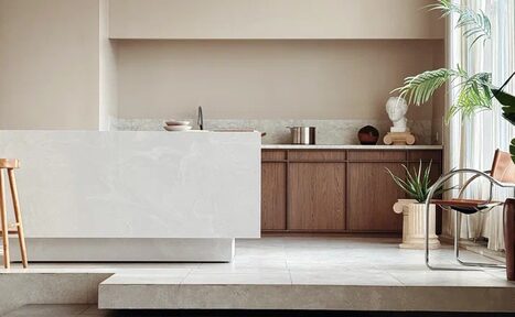 Арендовать Киото. Светлый зал с кухней. Современная кухня с островом; деревянные шкафы, мраморная столешница; высокая табуретка; декоративные растения; статуя на колонне; светлая обстановка; светлый плиточный пол; мягкое естественное освещение; бежевые и кремовые тона.