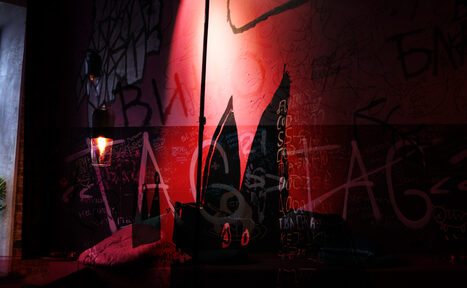 Арендовать Винный бар “Дело не в вине”. Креативное пространство с граффити на стенах, декоративный светильник с теплым освещением, мягкая мебель. Темные и насыщенные цвета, присутствует настенное искусство и текст в виде граффити.