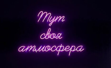 Арендовать Лофт «Блэкберри». Неоновая надпись на тёмном фоне: "Тут своя атмосфера". Цвет - фиолетовый.