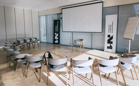Арендовать Лекторий на 53 этаже Москва-Сити - 100 м², до 35 человек. Конференц-зал с круговой расстановкой из деревянных стульев с мягкими сиденьями. Большой экран для проекций, флипчарт и два рекламных стенда. Светлое деревянное покрытие пола, естественное освещение через окна.