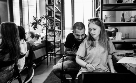 Арендовать Work Shop Loft(Воркшоп Лофт). Зал 11 . Современное пространство с окнами с жалюзи, полки и растения. На полу плитка и ковровое покрытие. Люди сидят за столами, видны стулья, диван и ноутбук. Присутствуют настольные лампы и документы на столе. Черно-белая гамма.