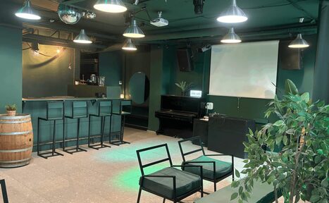 Арендовать Work Shop Loft(Воркшоп Лофт). Зал 11 . Лофт-пространство с баром, барные стулья, диваны, экран, пианино, деревянная бочка, зелёные стены, потолочные светильники, растительность в горшках, подвесные светильники.