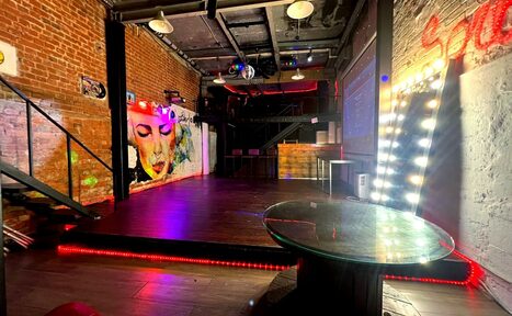 Арендовать Soul Loft . Крупный план угла большого зеркала и гирлянд на ней, всё расположено у кирпичной стены