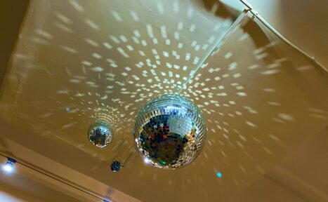 Арендовать Лофт для вечеринок с коктейльным баром . Потолок с двумя дискошарами, создающими световые узоры на поверхности. Потолок светло-бежевого цвета с видимыми частями электрической проводки. Споты на потолке обеспечивают дополнительное освещение.