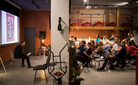 Арендовать Стильный двухуровневый лофт. Человек ведёт лекцию. Слушатели смотрят на экран и лектора