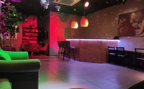 Арендовать Work Shop Loft(Воркшоп Лофт). Зал 9. Лофт-пространство с барной стойкой, высокими стульями и рядом со столами с креслами. Настенные светильники, зеленое и красное освещение, диско-шары. Стены с картинами, книжные полки. Потолок темный, пол плиточный светлый.