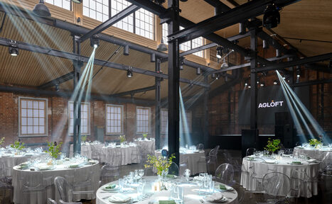 Арендовать AG Loft. Urban (АГ Лофт. Урбан). Просторный лофт с раритетным автомобилем. Просторное помещение с высоким потолком и большими окнами. Кирпичные стены, металлические балки. Круглые столы с белыми скатертями и прозрачными стульями. На столах посуда с приборами и вазы с зеленью. Освещение из прожекторов. Знак "AGLÓFT".