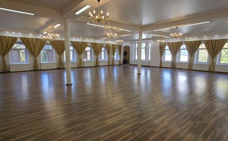 Арендовать Белый зал с колоннами и эркером. Просторный зал с деревянным полом, белыми стенами и колоннами. На потолке подвешены классические люстры. Большие окна с желтыми шторами по периметру. Естественное освещение. Зал пустой, без мебели.